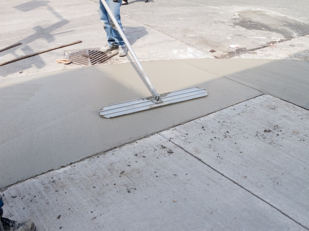 Worker resurfacing concrete sidewalk with hand float