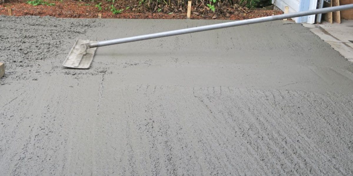 Freshly poured and smoothed wet concrete slab with screed board.